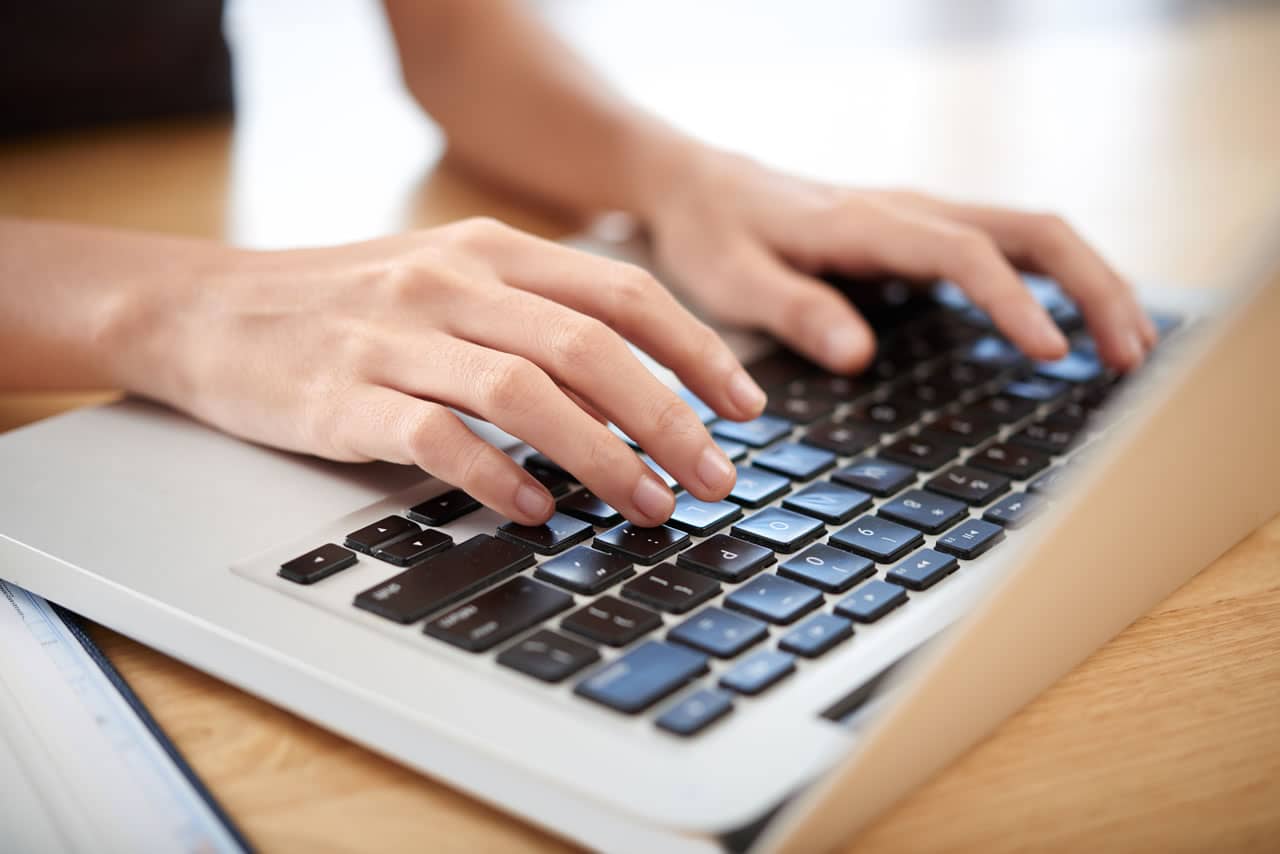Damenhände auf Laptoptastatur beim Onlinetraining